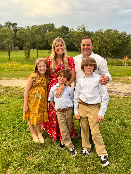 A family smiling in an open field.